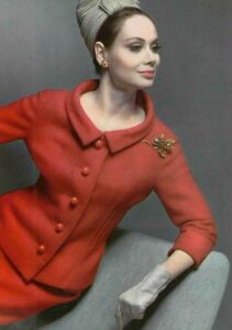 Model in poppy red wool suit, shaped jacket with round collar by Pierre Cardin, fruit pin also by Pierre Cardin, photo by Pottier, 1962